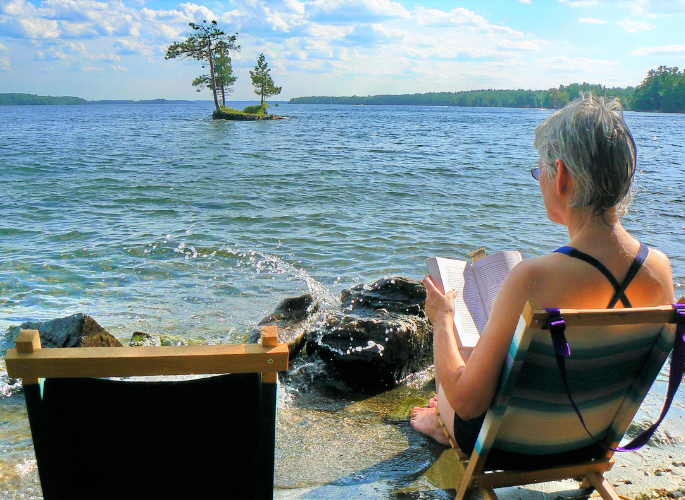 a woman reads a book by a cool lake