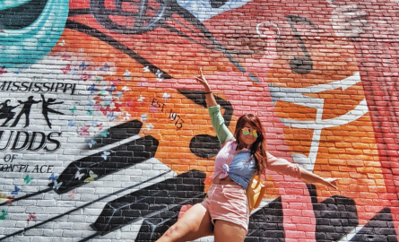 a girl poses in front of a mural