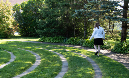 a woman walks along the path of a spiraling labyrinth