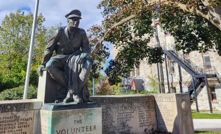 a statue of a young man in military dress seated on a stone