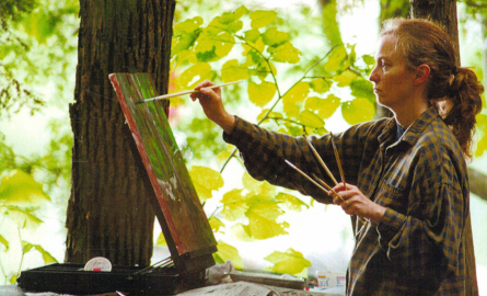 a woman painting in the woods