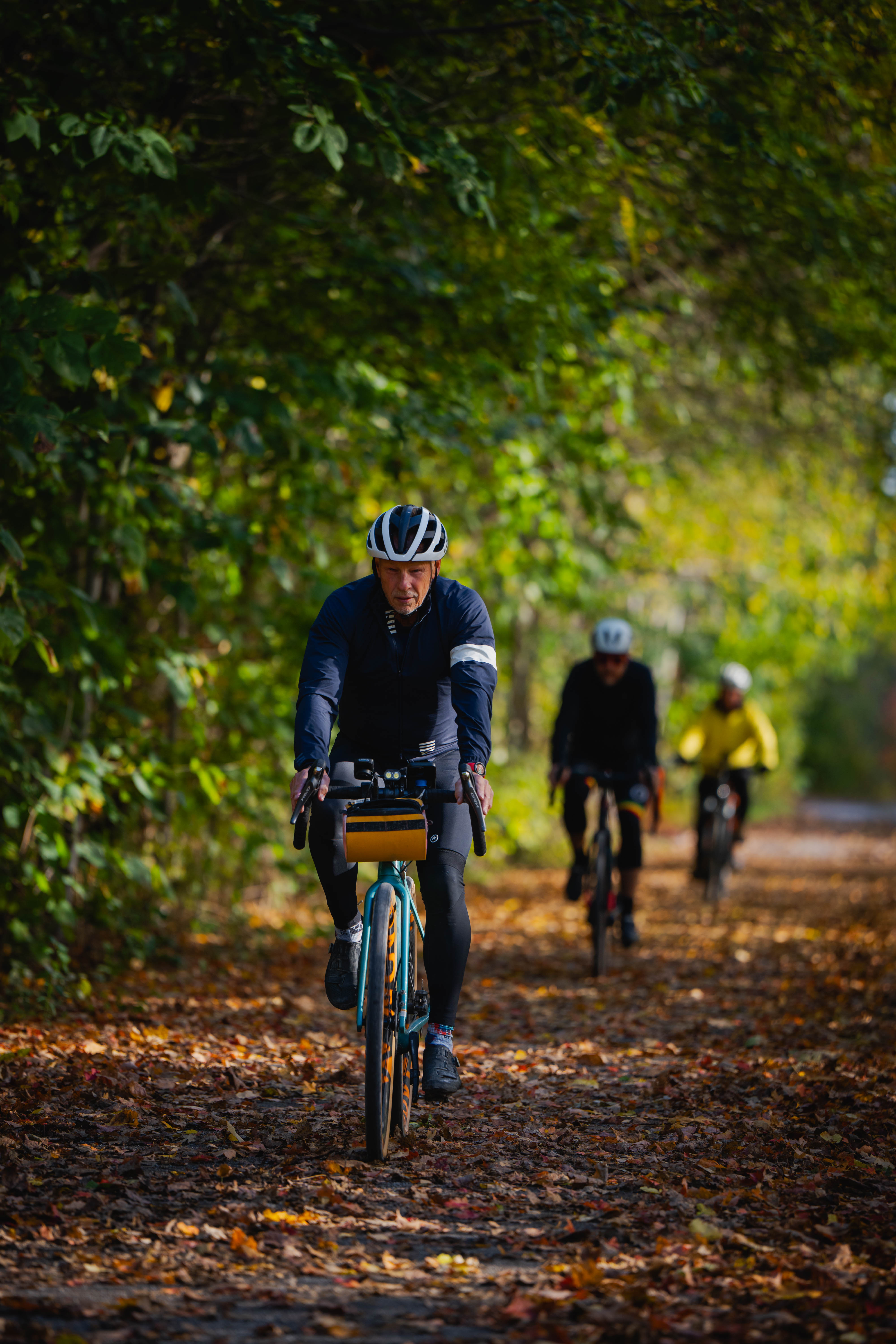cyclists travel along a tree-lined trail