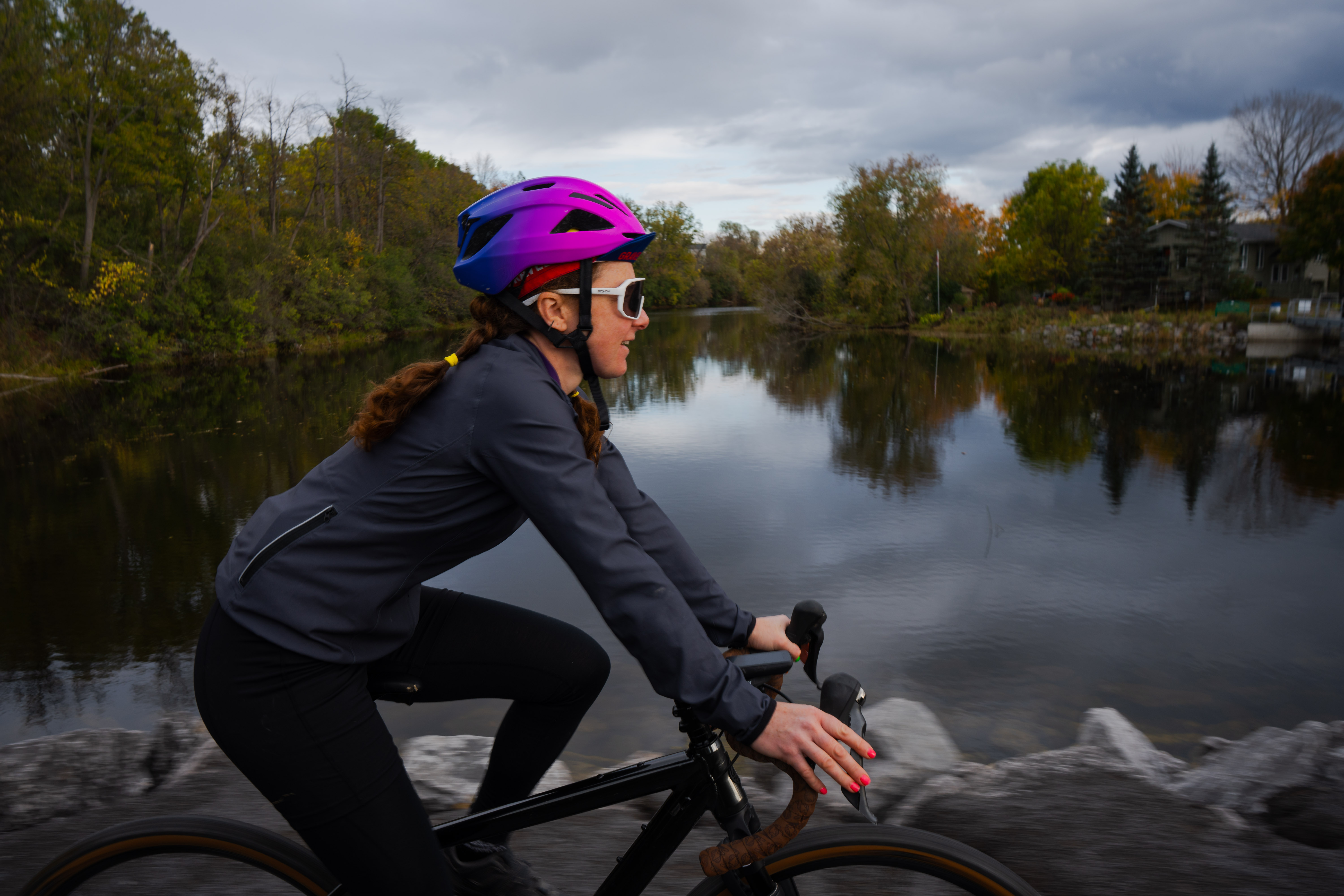 a woman rides a bicycle along a trail beside a lake