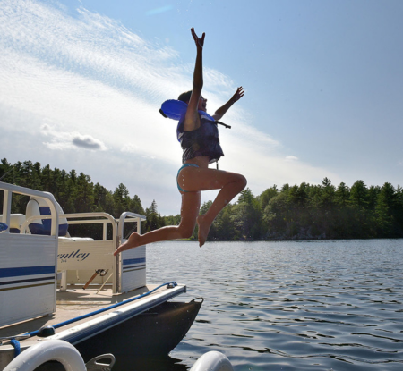 a girl joyfully jumps from a boat into the water