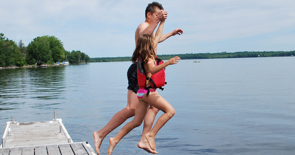 a father and daughter leap into a lake